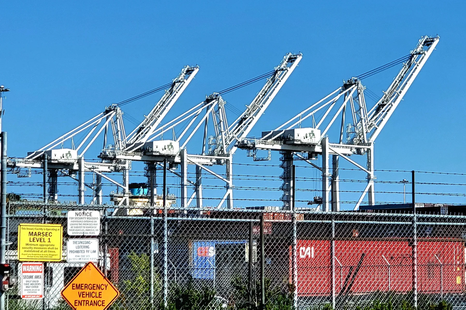 White container cranes rising over stacked containers at the Port of Oakland